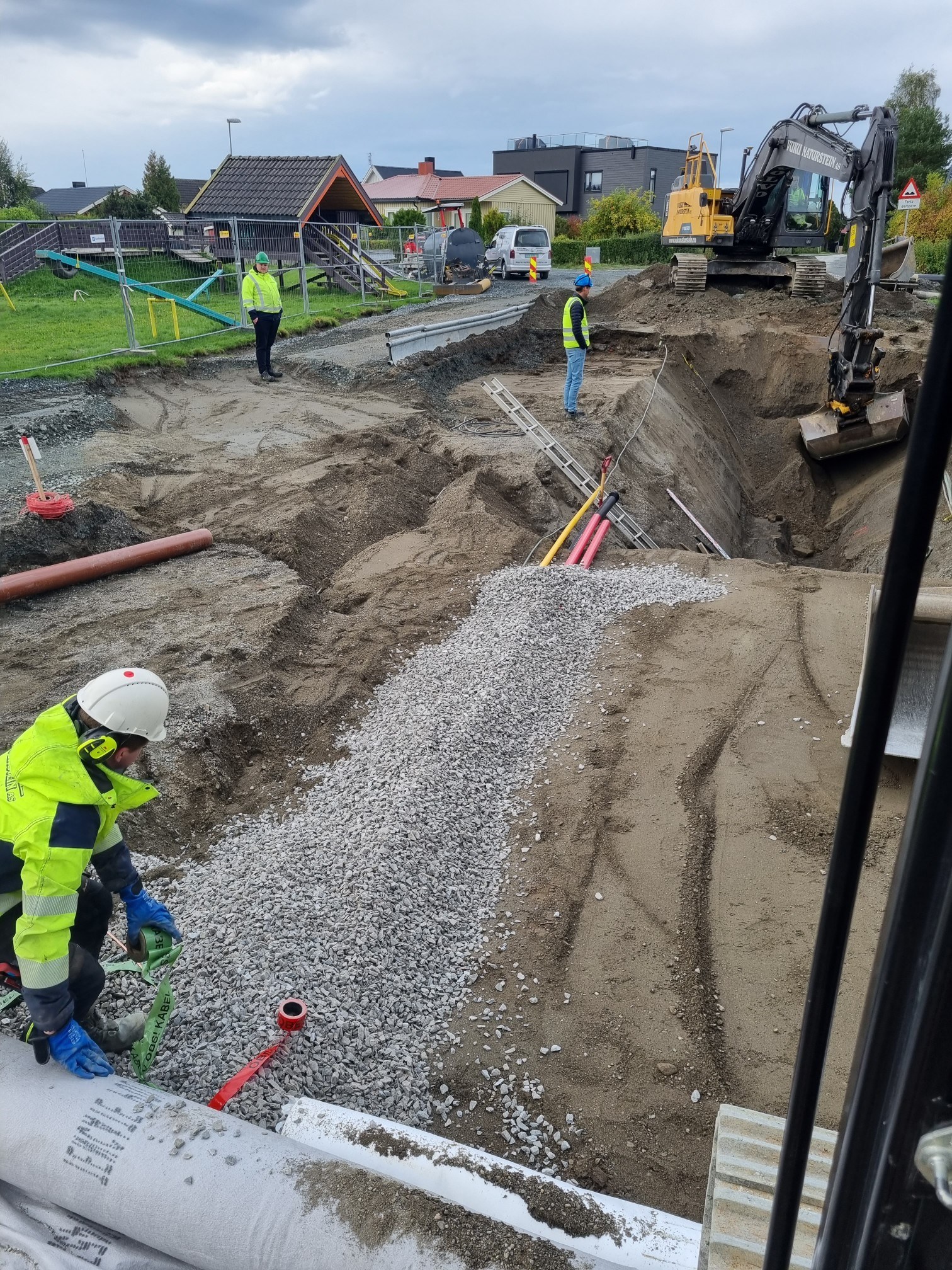 Mennesker som bedriver anleggs- og gravearbeid på vei i boligfelt